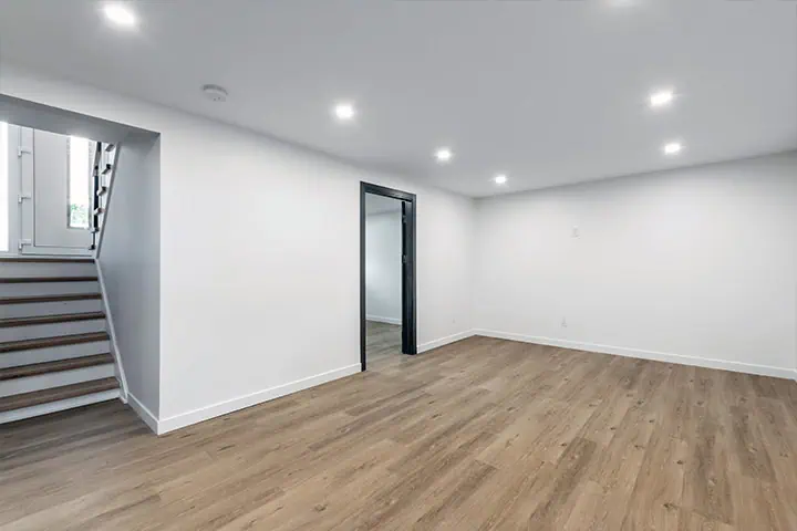 a finished basement with a door and a wood floor